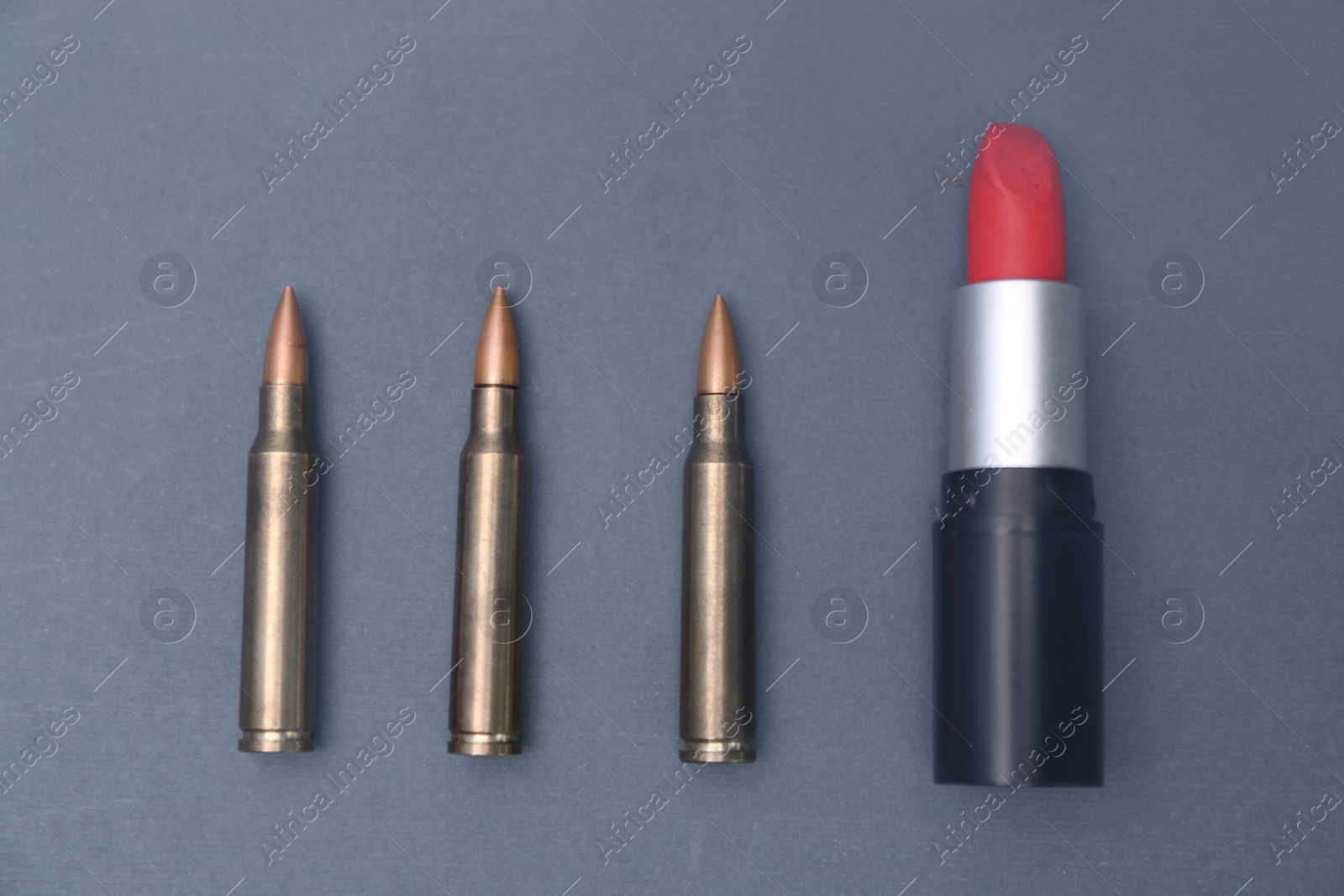 Photo of Red lipstick among bullets on grey background, flat lay