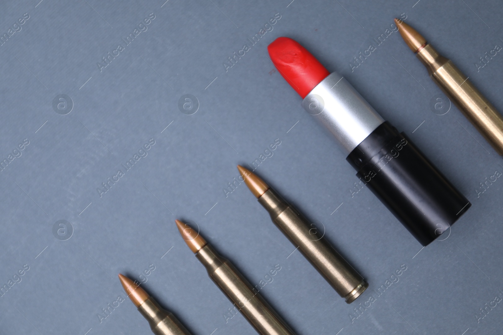 Photo of Red lipstick among bullets on grey background, flat lay. Space for text
