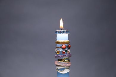 Photo of Burning candle with different rings on grey background