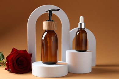 Photo of Promotion. Cosmetic products, podiums and rose flower on brown background