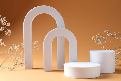 Photo of Promotion. Podiums for product presentation and gypsophila flowers on brown background