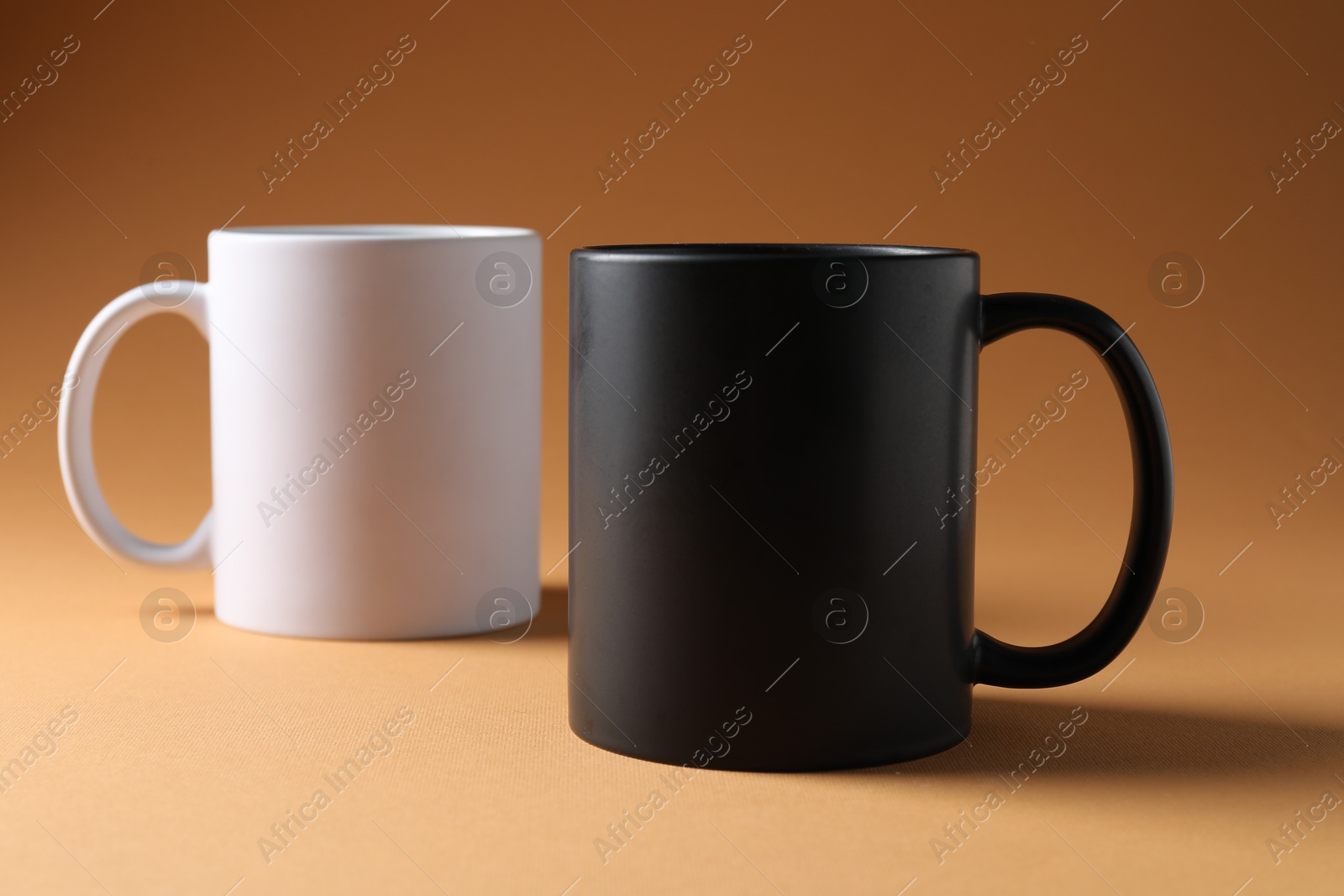 Promotion. White and black mugs on brown background Photo of Promotion. White and black mugs on brown background