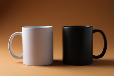 Photo of Promotion. White and black mugs on brown background