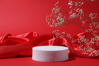 Photo of Promotion. Podium for product presentation, fabric and gypsophila flowers on red background