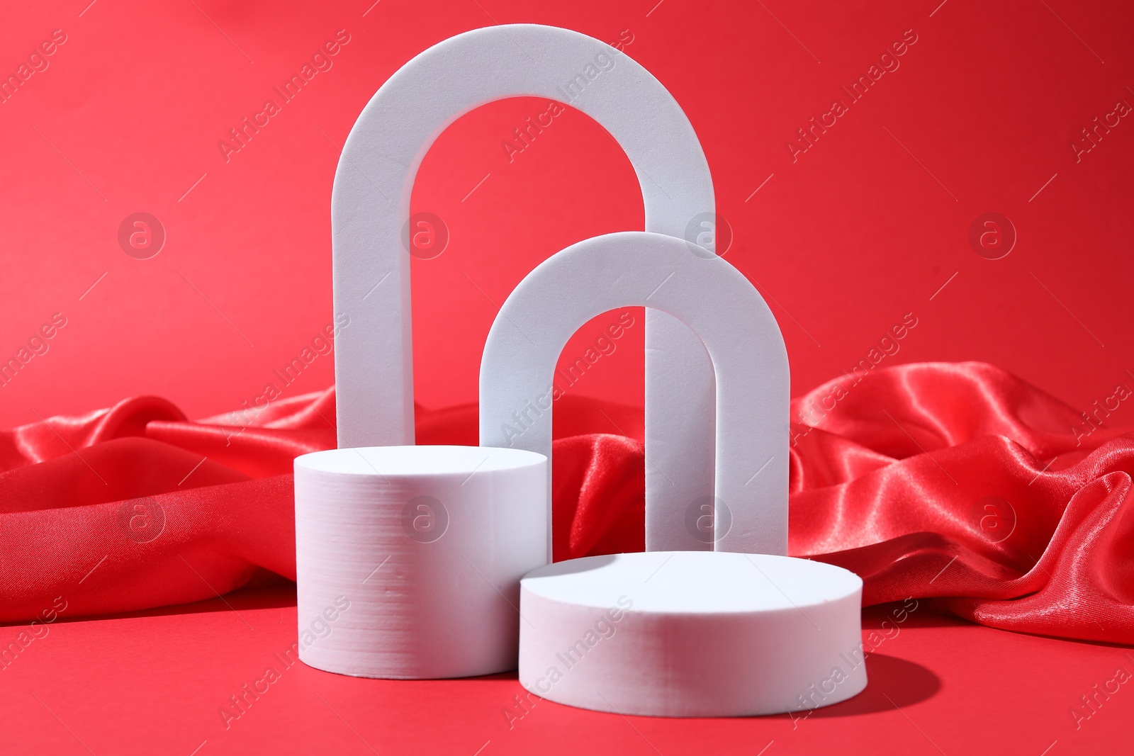 Photo of Promotion. Different podiums for product presentation and fabric on red background