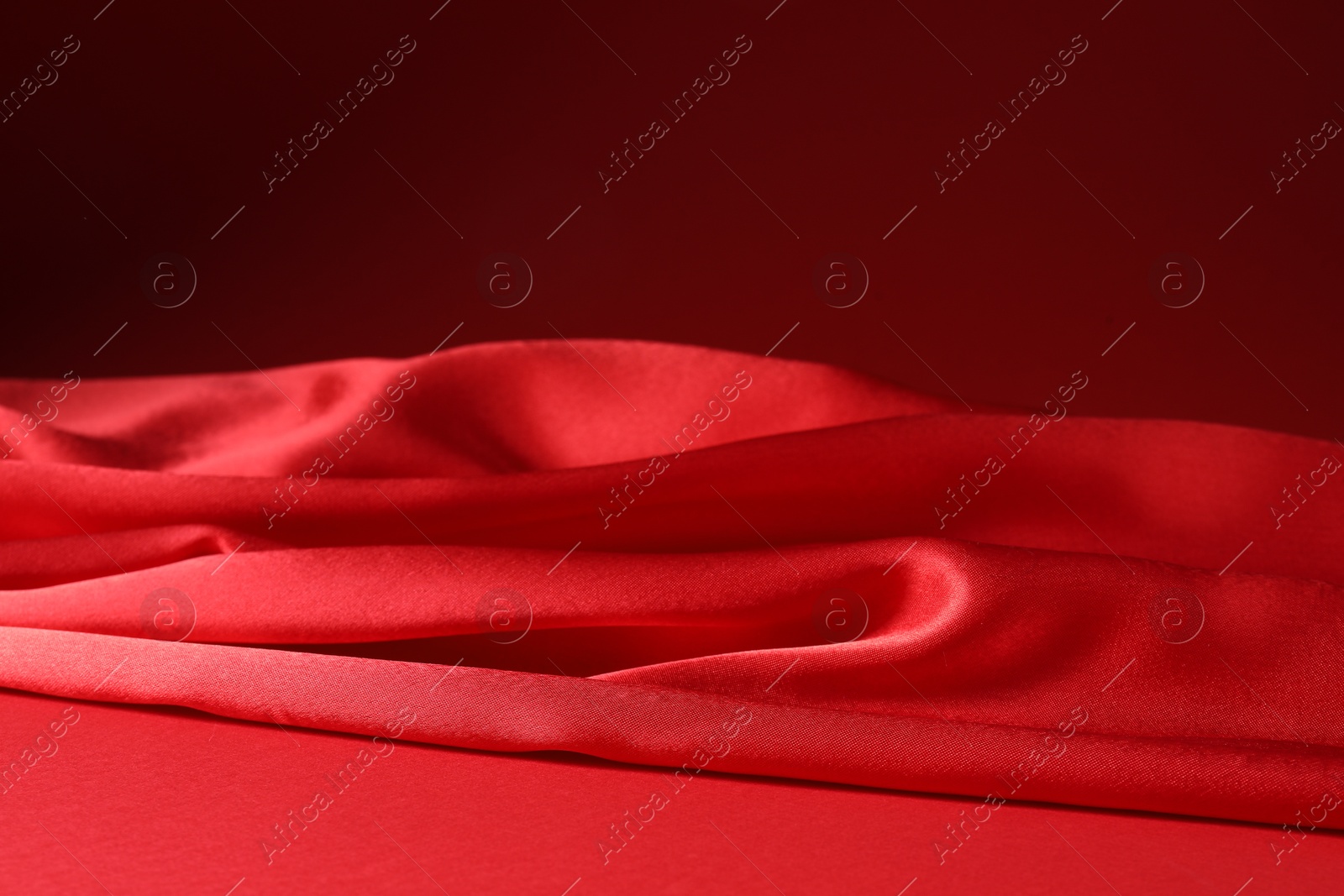 Photo of Promotion. Beautiful red silk fabric on color background, closeup