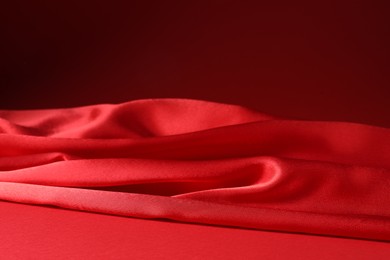 Photo of Promotion. Beautiful red silk fabric on color background, closeup