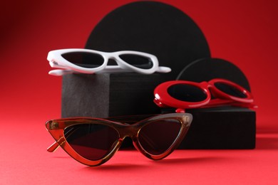 Photo of Promotion. Stylish sunglasses and podiums on red background