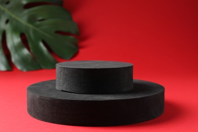 Photo of Promotion. Podiums for product presentation and monstera leaf on red background