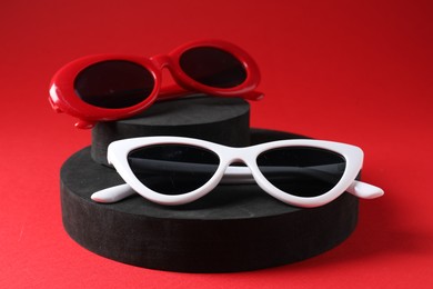 Photo of Promotion. Stylish sunglasses and podiums on red background