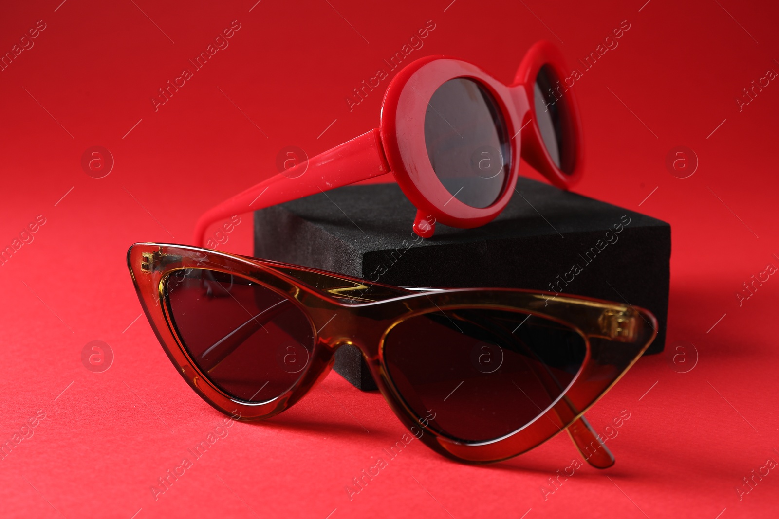 Photo of Promotion. Stylish sunglasses and podium on red background