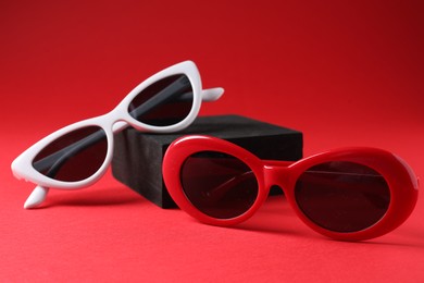 Photo of Promotion. Stylish sunglasses and podium on red background