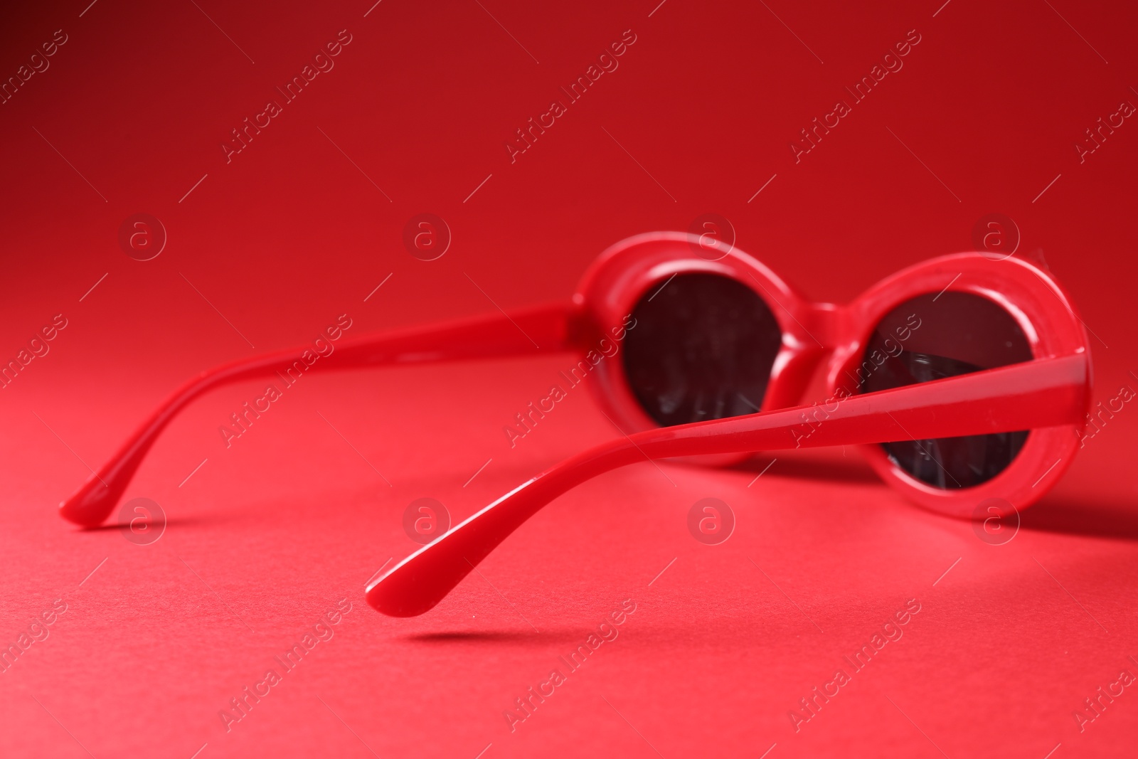 Photo of Promotion. Stylish sunglasses on red background, closeup