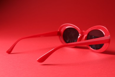Photo of Promotion. Stylish sunglasses on red background, closeup