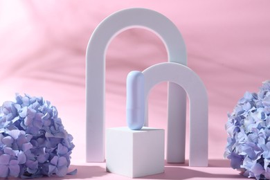 Photo of Promotion. Cosmetic product, white figures and hydrangea flowers on pink background, closeup