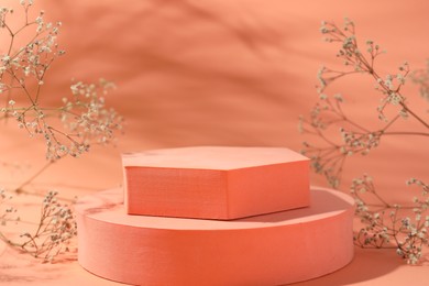 Photo of Promotion. Podiums for product presentation and gypsophila flowers on coral background