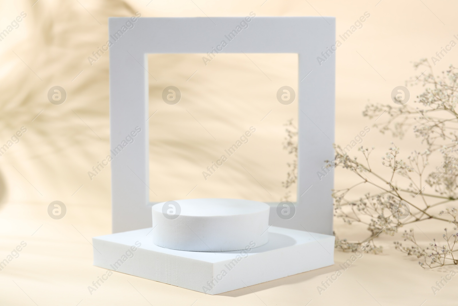 Photo of Promotion. Different podiums for product presentation and gypsophila flowers on beige background
