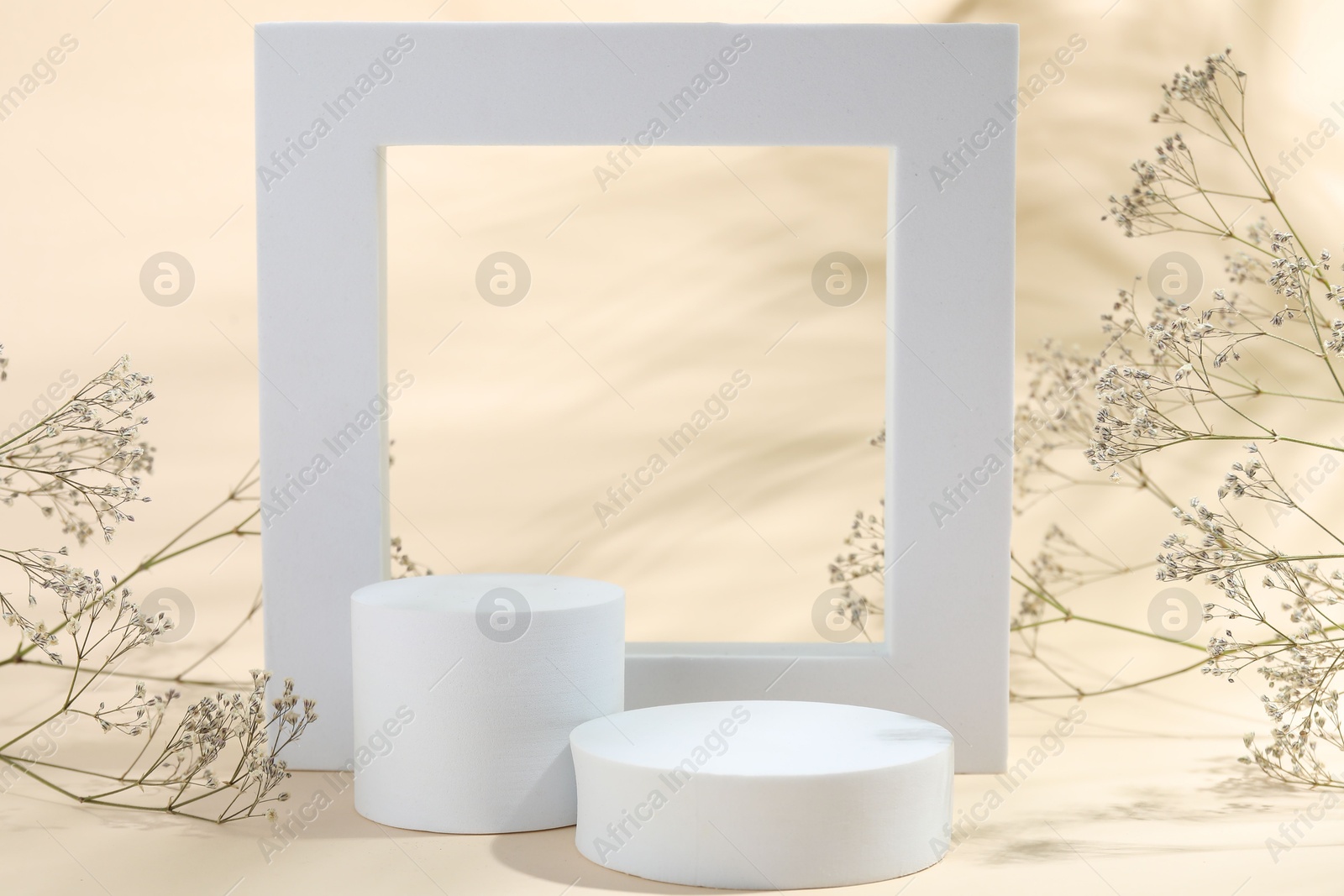 Photo of Promotion. Different podiums for product presentation and gypsophila flowers on beige background