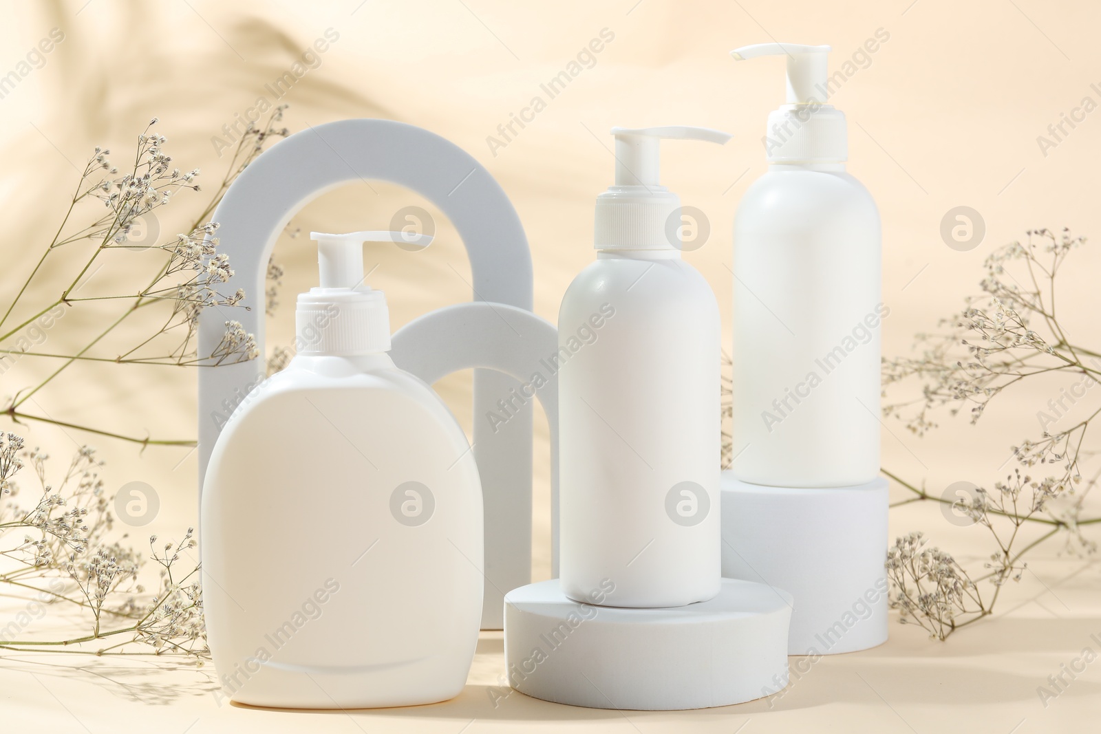 Photo of Promotion. Cosmetic products, podiums and gypsophila flowers on beige background
