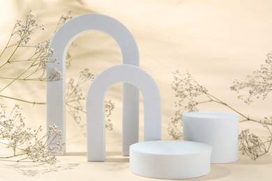 Photo of Promotion. Different podiums for product presentation and gypsophila flowers on beige background