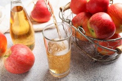Photo of Pouring delicious cider into glass at light grey table, closeup