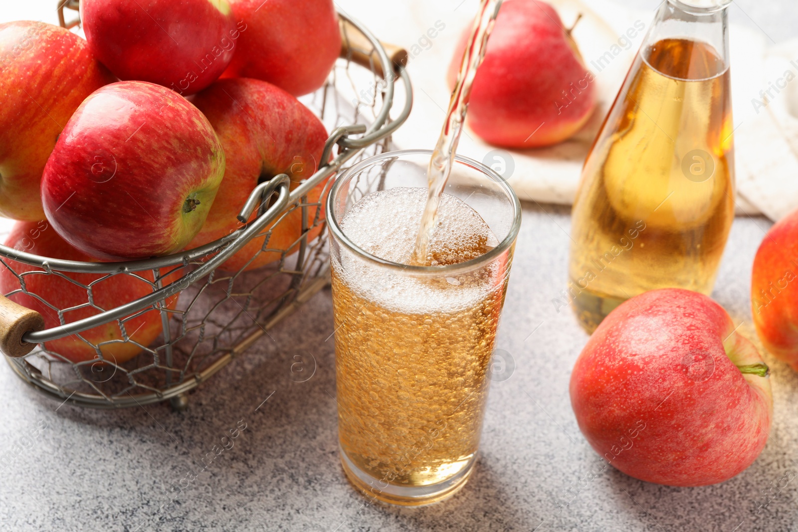 Photo of Pouring delicious cider into glass at light grey table, closeup
