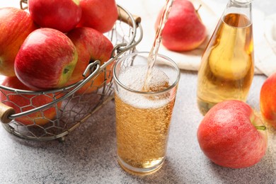 Photo of Pouring delicious cider into glass at light grey table, closeup