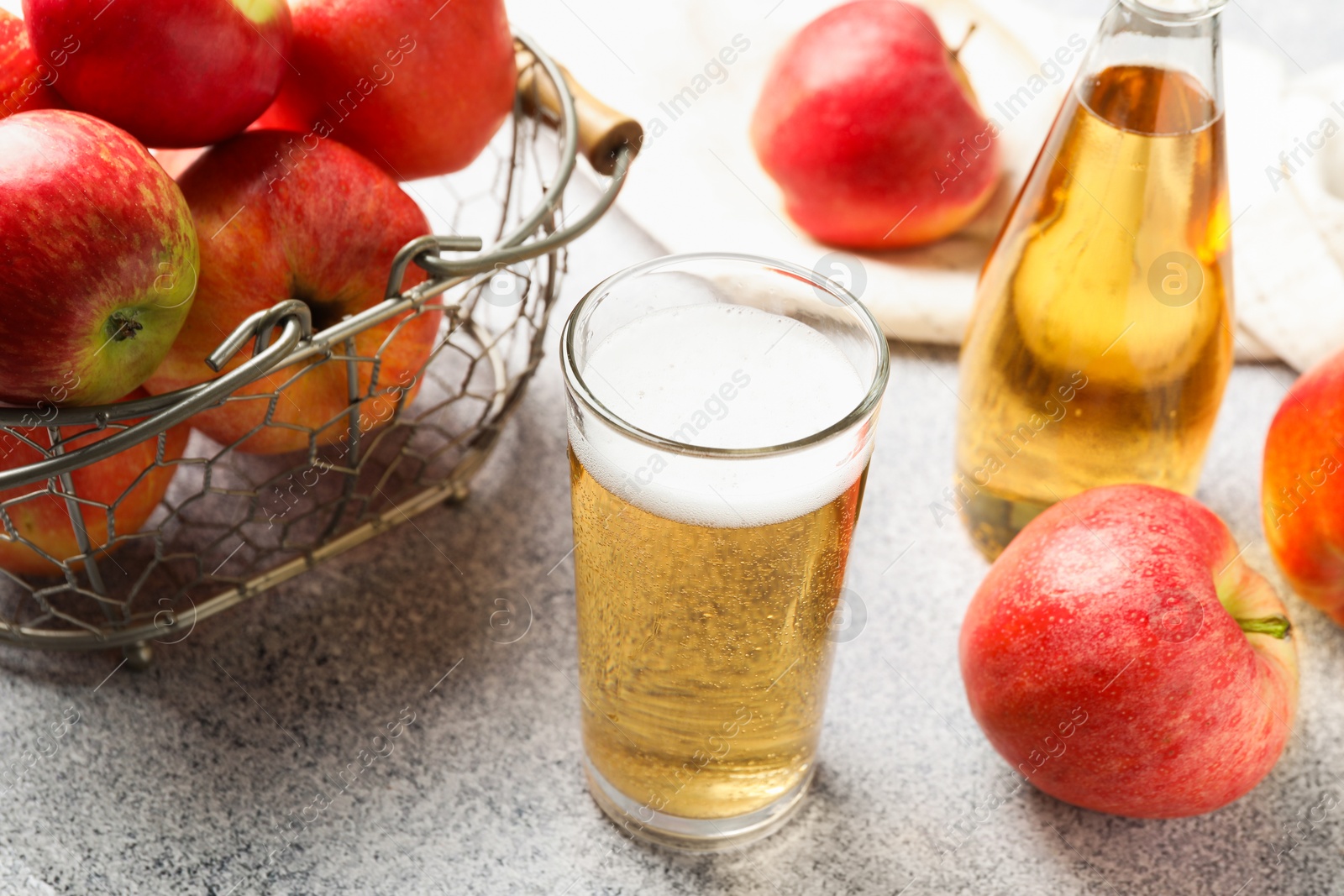Delicious cider in glass, bottle and apples on light grey table, closeup Photo of Delicious cider in glass, bottle and apples on light grey table, closeup