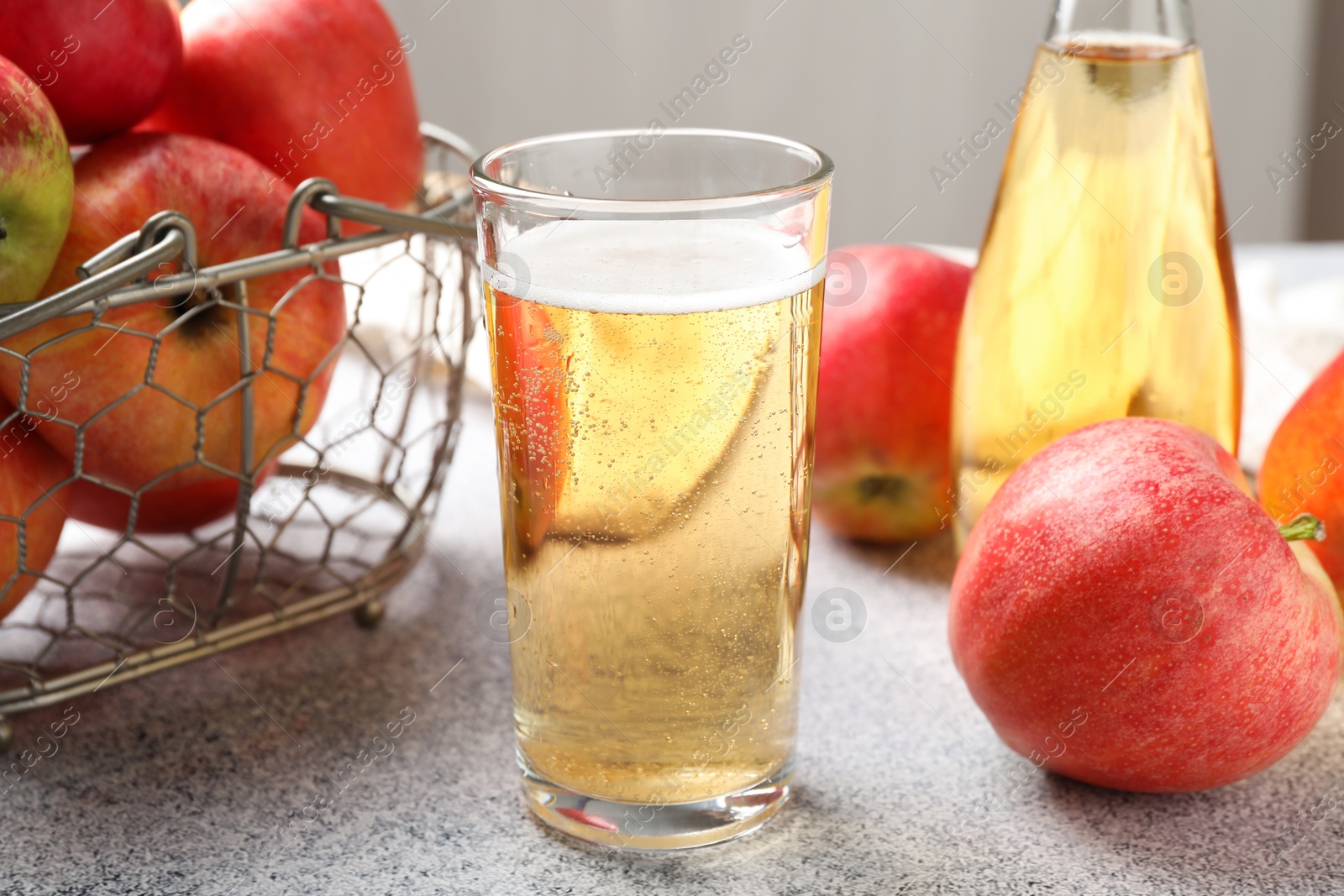 Delicious cider in glass, bottle and apples on light grey table, closeup Photo of Delicious cider in glass, bottle and apples on light grey table, closeup