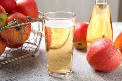 Photo of Delicious cider in glass, bottle and apples on light grey table, closeup