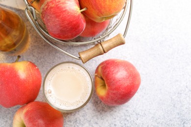 Photo of Delicious cider in glass, bottle and apples on light grey table, flat lay. Space for text