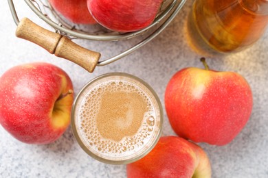 Photo of Delicious cider in glass, bottle and apples on light grey table, flat lay