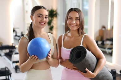 Photo of Women with fitness mat and ball in pilates studio