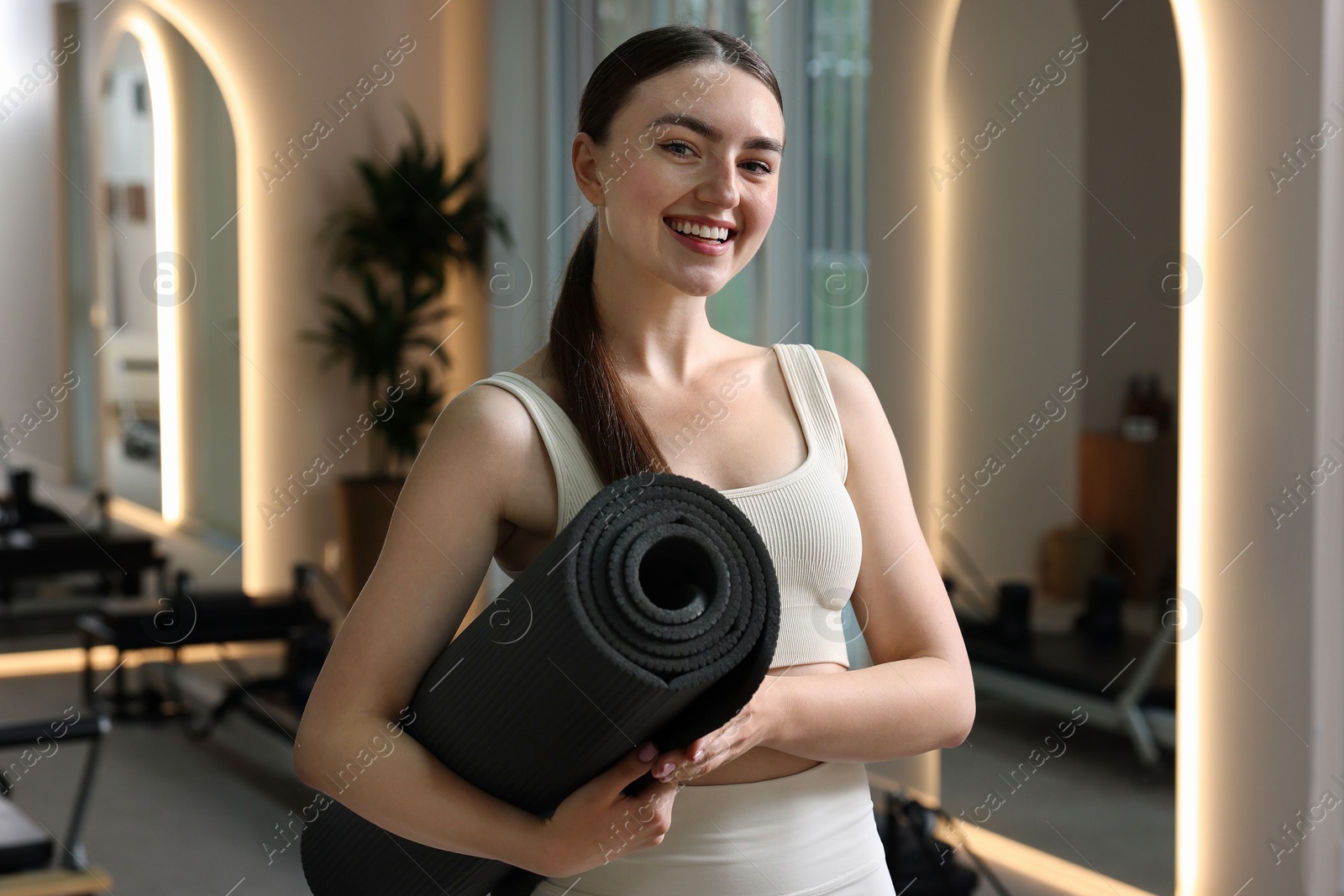 Woman with fitness mat in pilates studio Photo of Woman with fitness mat in pilates studio