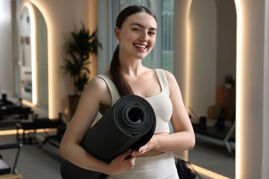 Photo of Woman with fitness mat in pilates studio