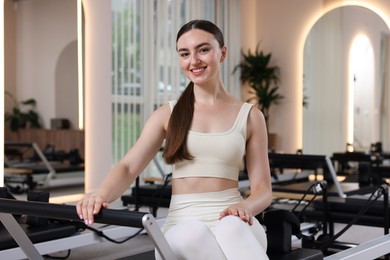 Photo of Woman sitting on reformer in pilates studio