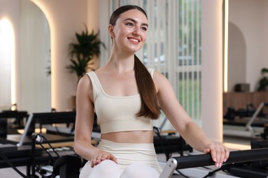 Photo of Woman sitting on reformer in pilates studio