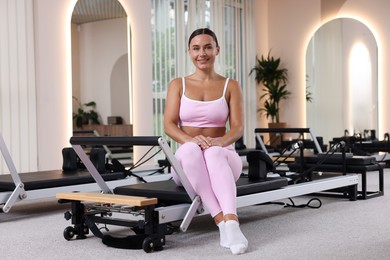 Photo of Woman sitting on reformer in pilates studio