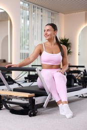 Photo of Woman sitting on reformer in pilates studio