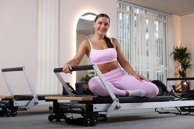 Photo of Woman sitting on reformer in pilates studio