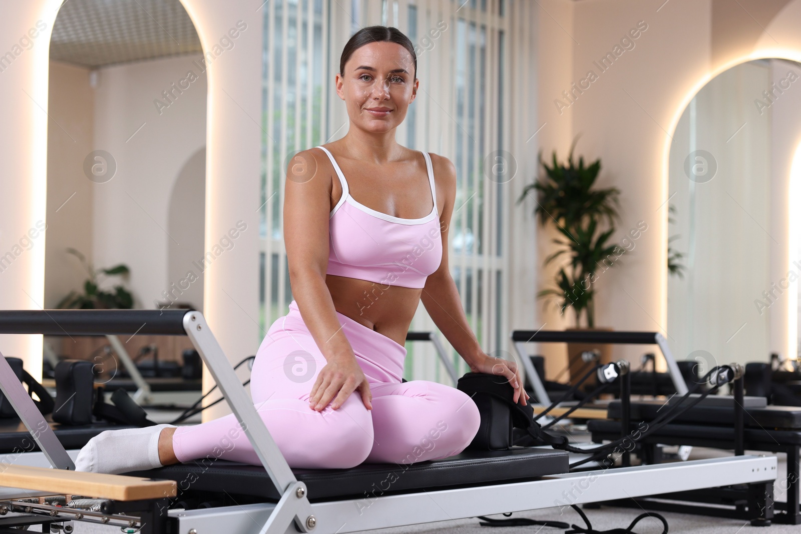 Photo of Woman sitting on reformer in pilates studio