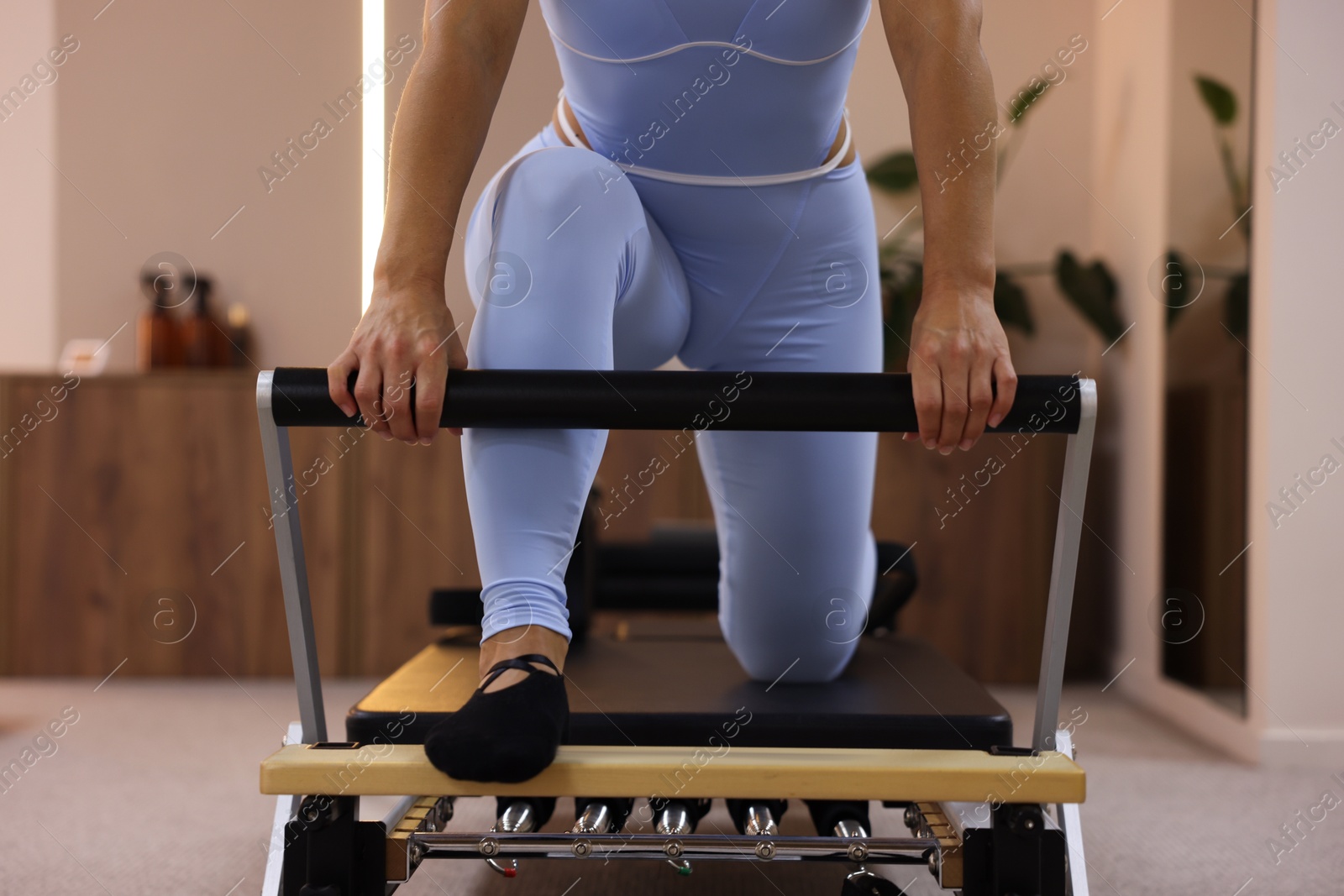 Woman exercising on reformer in pilates studio, closeup Photo of Woman exercising on reformer in pilates studio, closeup