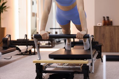 Photo of Woman exercising on reformer in pilates studio, closeup