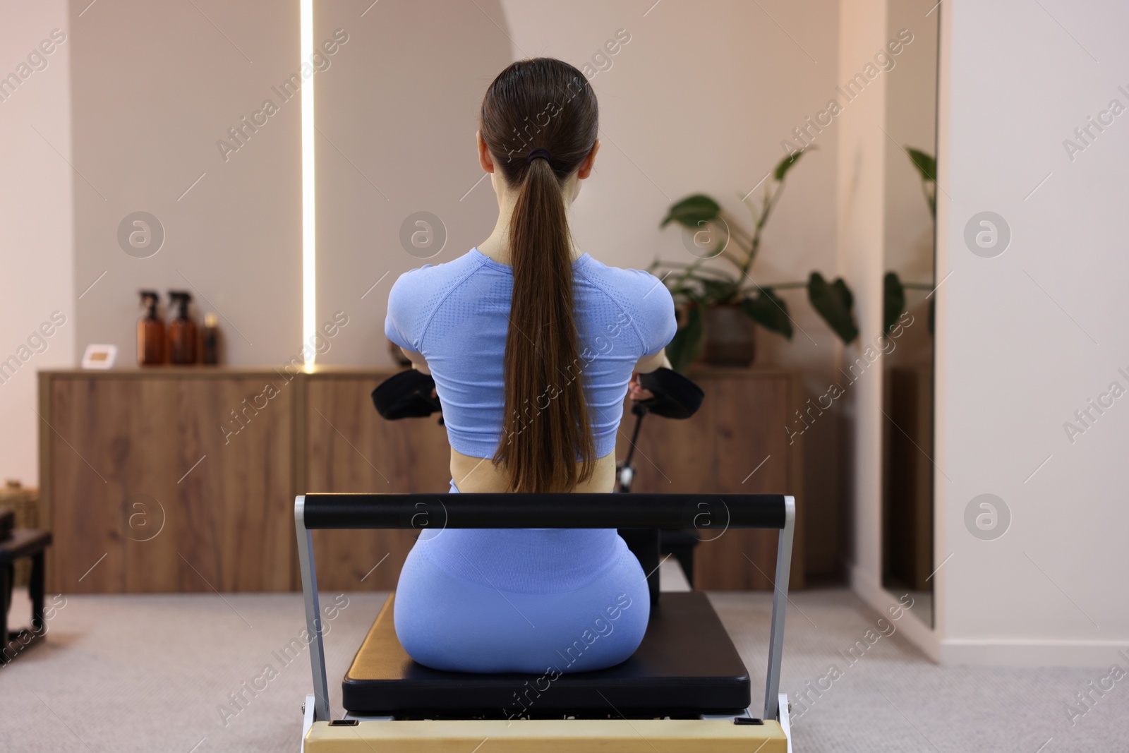 Woman exercising on reformer in pilates studio, back view Photo of Woman exercising on reformer in pilates studio, back view