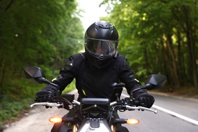 Photo of Young man in helmet driving modern motorcycle outdoors