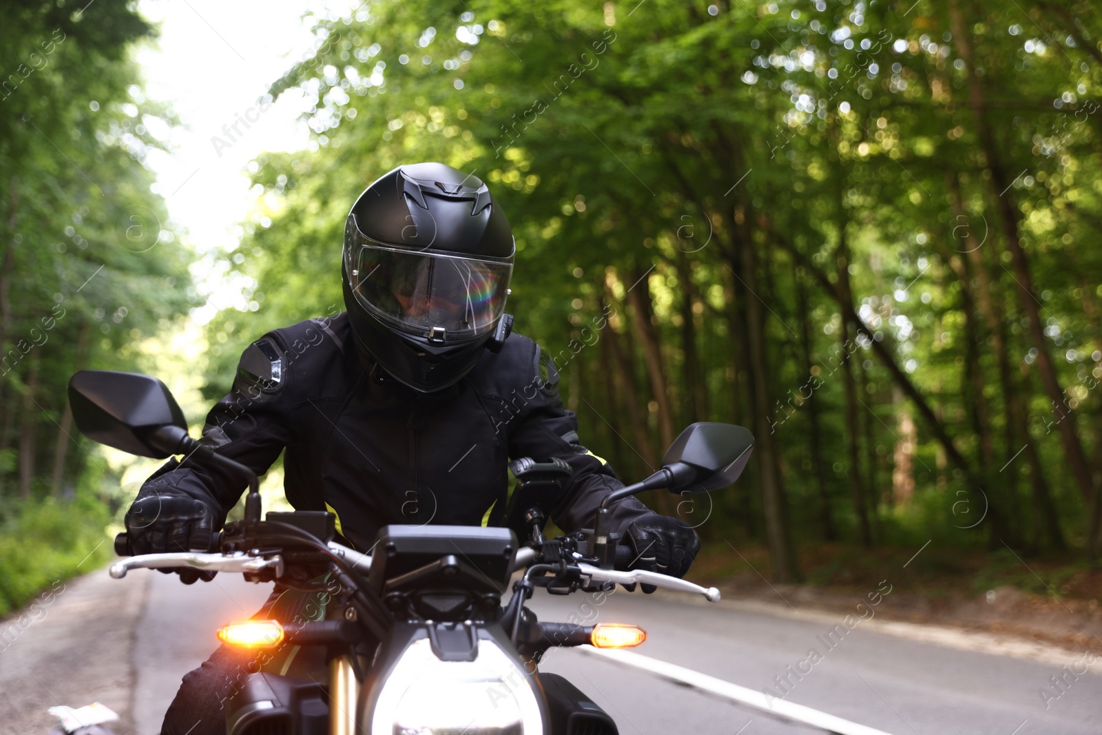 Young man in helmet driving modern motorcycle outdoors. Space for text Photo of Young man in helmet driving modern motorcycle outdoors. Space for text
