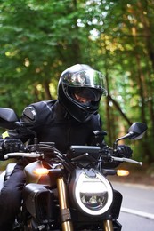 Photo of Young man in helmet driving modern motorcycle outdoors