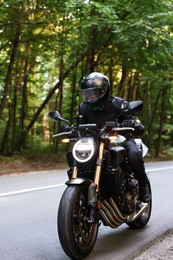 Photo of Young man in helmet driving modern motorcycle outdoors