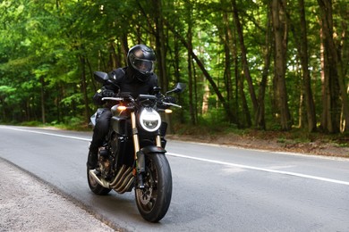 Photo of Young man in helmet driving modern motorcycle outdoors. Space for text