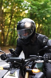Photo of Young man in helmet driving modern motorcycle outdoors